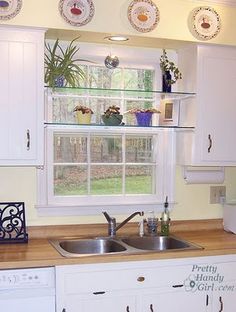 a kitchen with white cabinets and wooden counter tops, including a window over the sink