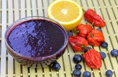 a glass bowl filled with blueberry sauce next to sliced oranges and strawberries