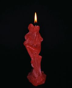 a candle that is lit in the dark with a red waxy substance on it