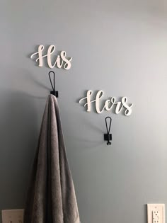 two towel hooks on the wall with his and her letters hanging from it's hooks