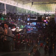 a crowd of people standing around an escalator at a convention or expo center