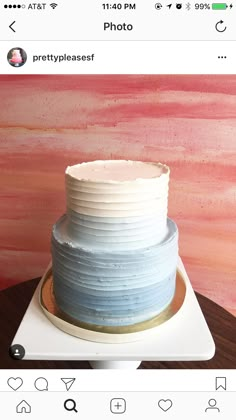 a white and blue cake sitting on top of a wooden table next to a pink wall