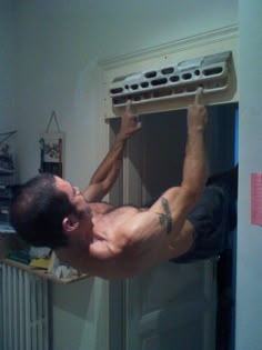 a shirtless man hanging upside down on an air conditioner