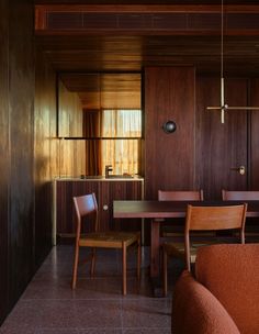 a dining room table and chairs in front of a wooden wall with wood paneling