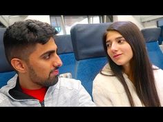 a man and woman are sitting on a train looking into each other's eyes