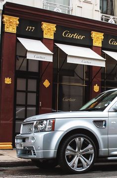 a silver range rover parked in front of a store