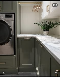 a washer and dryer sitting in a kitchen next to a counter with potted plants