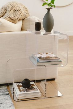 a white couch sitting next to a table with a vase on top of it and books