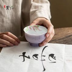 a person holding a bowl over a paper with writing on it