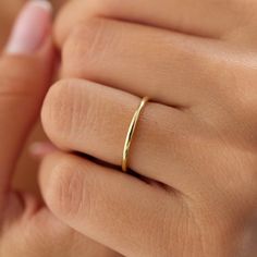 a woman's hand with a gold wedding ring on her left hand and the other hand holding it