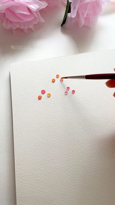 someone is painting flowers with watercolors on paper