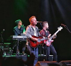 two men on stage playing guitars and singing