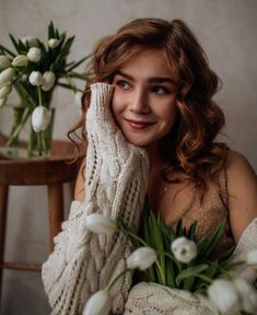 a woman sitting on a chair with flowers in front of her and smiling at the camera