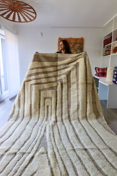 a woman laying on top of a bed covered in a large white and brown blanket