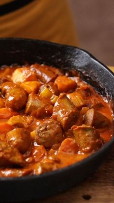 a pan filled with meatballs and carrots on top of a wooden table