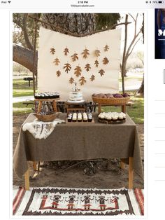 a table topped with cupcakes and cakes under a tree