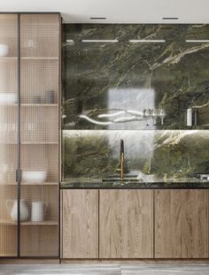 a kitchen with green marble counter tops and wooden cabinetry, along with glass shelves