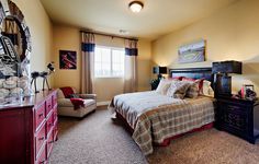 a bedroom with a bed, dresser and chair in the corner next to a window