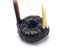 two candles are in a black holder on a white surface, one is red and the other is yellow