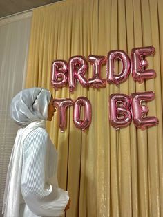 a woman standing in front of balloons that say bride to be