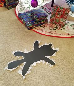 a cat cut out on the floor next to presents