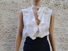 This ivory white sleeveless blouse is essential to any well-edited wardrobe. Laid back yet chic, it's crafted in 100% pure silk with a pleat relaxed shape and flattering / boat neckline. Perfect for event, work or off-duty dressing it will take you through the new season and beyond. * Measurements: Size S  Bust :50 cm ( 20'' in)- laying flat measured from one armpit to the other. Hips :54 ( 21'' in) Long : 56 cm ( 22'' in)- length measurement is taken from top of the front shoulder to hem. Size Elegant V-neck Top With Bow, Elegant V-neck Blouse For Summer, Classic V-neck Party Top, White Tie Neck Blouse For Formal Occasions, Elegant Fitted Tie Neck Blouse, Elegant Tie Neck Blouse For Daywear, Feminine Tie Neck Formal Tops, Feminine Formal Tie Neck Tops, Feminine Tie Neck Tops For Formal Occasions