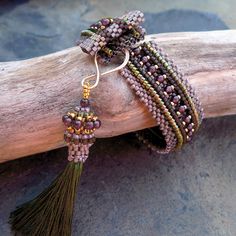 bracelets with beads and tassels are sitting on a branch