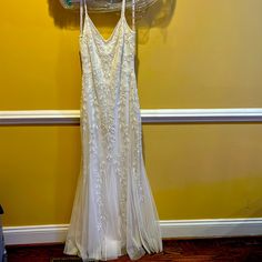 a wedding dress hanging on a rack in front of a yellow wall