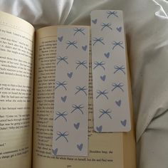 two bookmarks with blue hearts on them are laying next to an open book