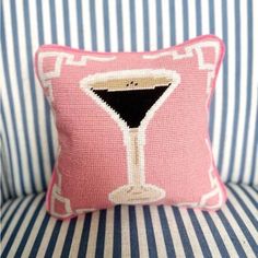 a pink and white striped couch with a pillow that has a martini glass on it