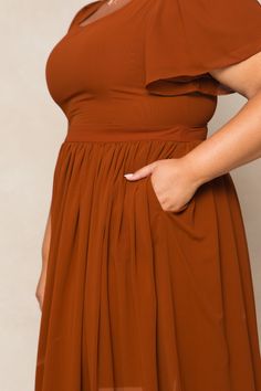 a woman in a brown dress with her hands on her hips and one hand on her hip