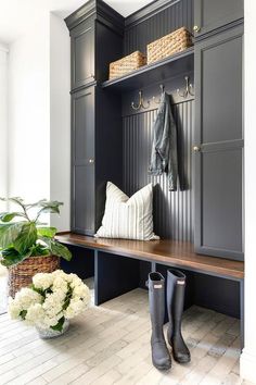 a bench with boots, coat rack and flowers in front of it on the floor