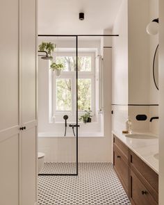 a bathroom with a black and white checkerboard floor, sink, shower stall and window