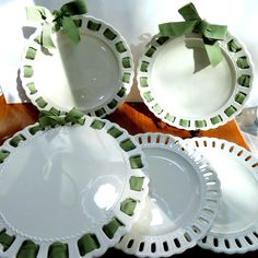 four white plates with green bows on them sitting on a wooden table next to each other