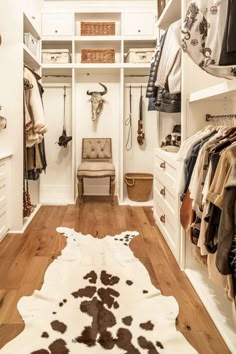 a walk in closet with white walls and wooden flooring, an animal print rug on the floor