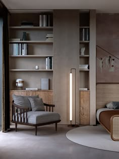 a bed room with a neatly made bed next to a chair and bookshelf