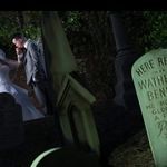 a bride and groom standing in front of a grave