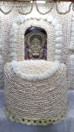 a sculpture made out of beads with a face on it's head in the center