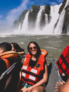 two people on a boat in front of a waterfall