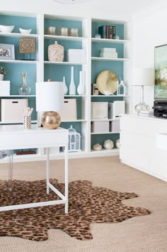 a white desk sitting in front of a book shelf filled with lots of books on top of