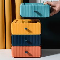 three colorful storage containers are stacked on top of each other in front of a window