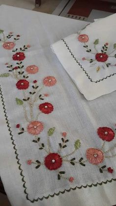 two white tablecloths with red flowers on them