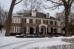 a large red brick house with white trim and windows in the front yard covered in snow