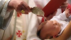 a baby is being held by a priest