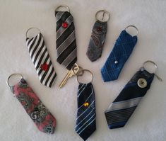 six different neck ties and keychains on a white surface, with one being held by a pair of scissors