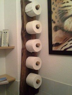 there are several rolls of toilet paper hanging on the wall in this bathroom, along with two pictures