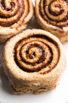 three cinnamon rolls on a white plate with brown sugar in the middle and chocolate filling