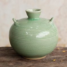 a green vase sitting on top of a wooden table