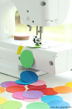 a sewing machine with colorful circles on the table next to it and a piece of paper that has been sewn