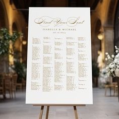 a white sign with gold lettering on it in front of a room filled with tables and chairs